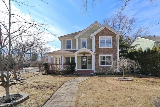 view of front of house with stone siding, covered porch, and a front yard