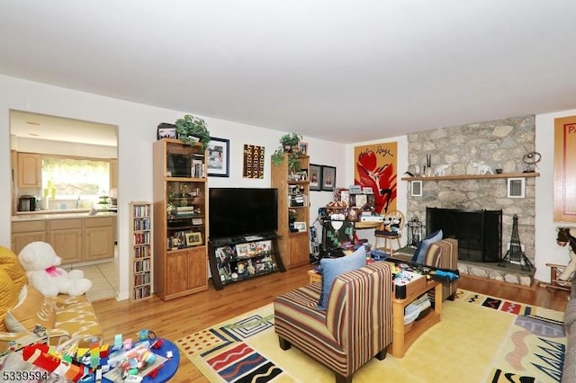 living area with light wood-style floors, a stone fireplace, and visible vents