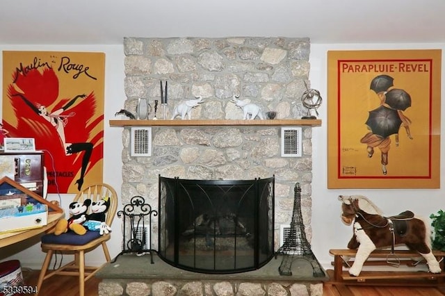 room details featuring visible vents, wood finished floors, and a stone fireplace