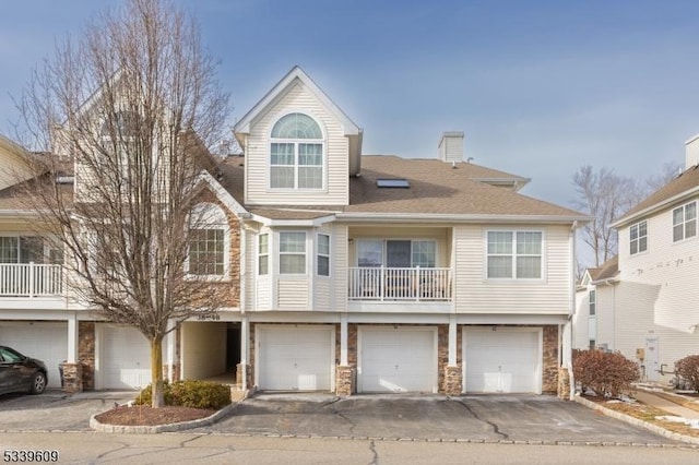 view of front of home featuring a garage, stone siding, and driveway