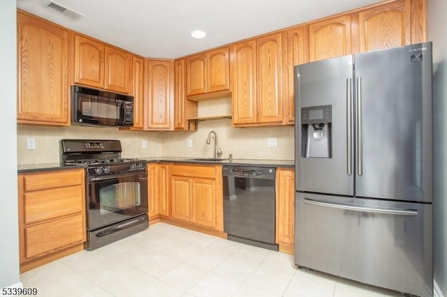 kitchen with tasteful backsplash, visible vents, dark countertops, black appliances, and a sink