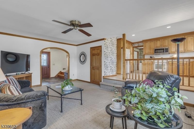 living area featuring baseboards, arched walkways, a ceiling fan, ornamental molding, and recessed lighting