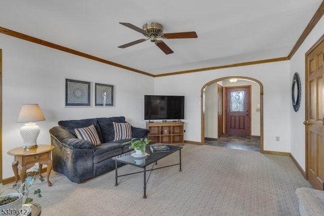 carpeted living area featuring arched walkways, ceiling fan, baseboards, and crown molding