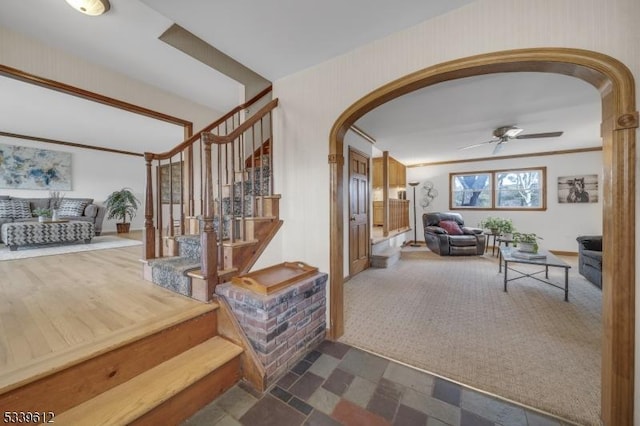 hallway with stairs, arched walkways, and dark colored carpet