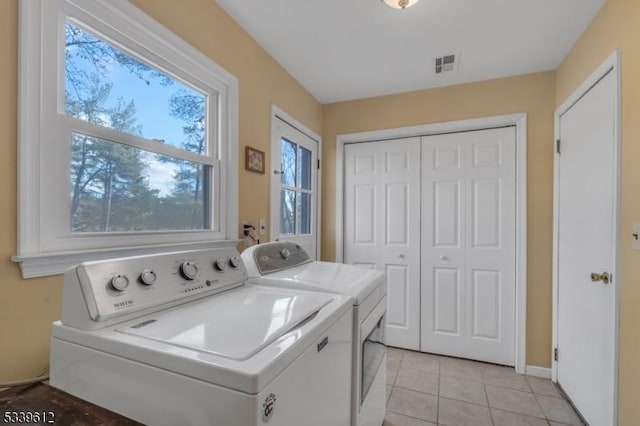 clothes washing area with light tile patterned floors, laundry area, washer and clothes dryer, and visible vents