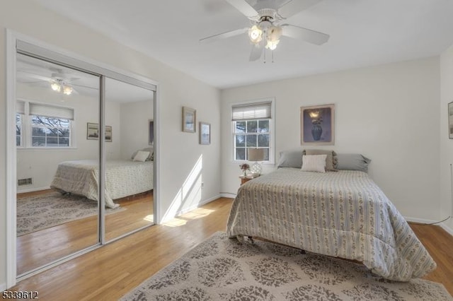 bedroom featuring baseboards, visible vents, a ceiling fan, wood finished floors, and a closet