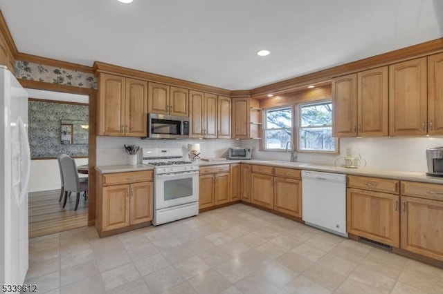 kitchen featuring white appliances, a sink, visible vents, light countertops, and wallpapered walls