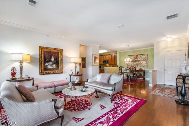 living room featuring ornamental molding, visible vents, baseboards, and wood finished floors