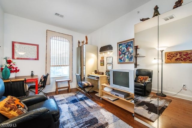 living room with visible vents, baseboards, and wood finished floors