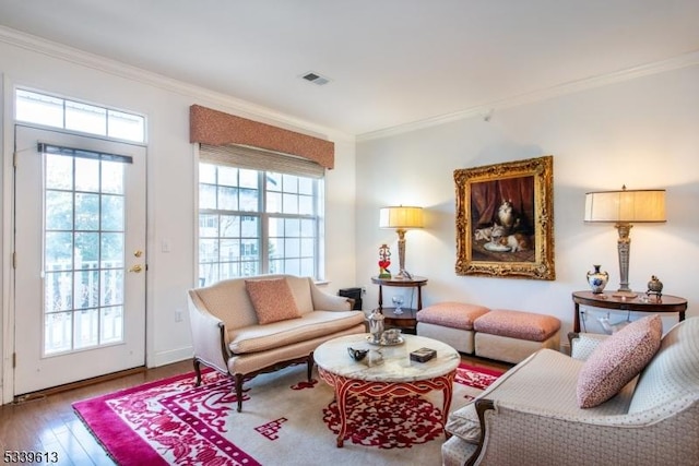 living room featuring plenty of natural light, visible vents, and ornamental molding