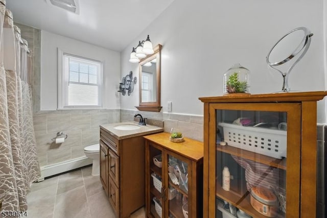 bathroom with toilet, vanity, tile walls, baseboard heating, and tile patterned floors