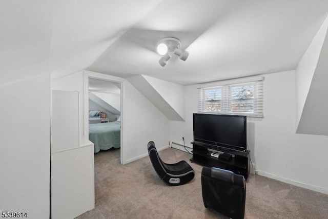 sitting room featuring lofted ceiling, baseboards, a baseboard heating unit, and light colored carpet