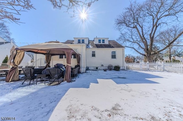 snow covered back of property with fence and a gazebo