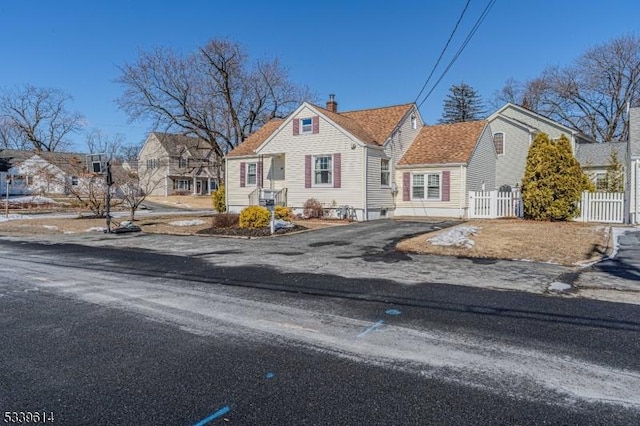 view of front of property with driveway, a chimney, a residential view, and fence