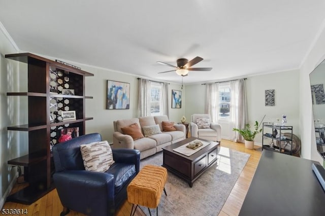 living area featuring ornamental molding, light wood finished floors, a ceiling fan, and baseboards