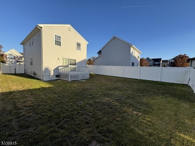 rear view of property featuring a lawn and a fenced backyard