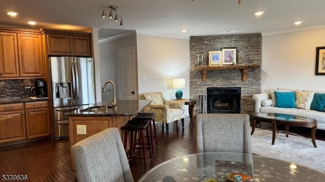 kitchen with dark wood-style flooring, open floor plan, dark stone countertops, and stainless steel fridge with ice dispenser