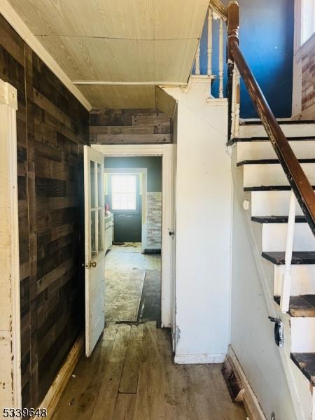 hallway featuring stairs, wood walls, and wood finished floors