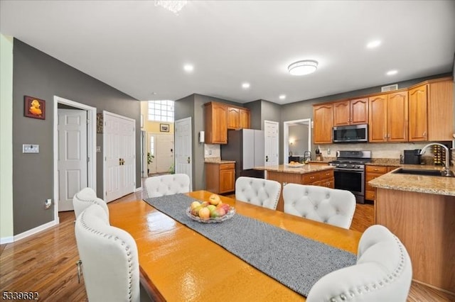 kitchen with a kitchen island, stainless steel appliances, light wood-style floors, a sink, and recessed lighting