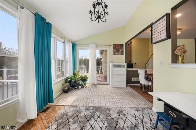 sunroom with lofted ceiling, visible vents, and a notable chandelier