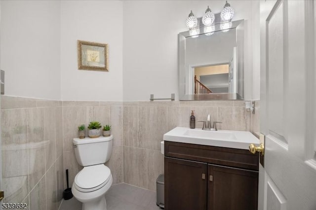 bathroom featuring toilet, tile patterned floors, tile walls, and vanity