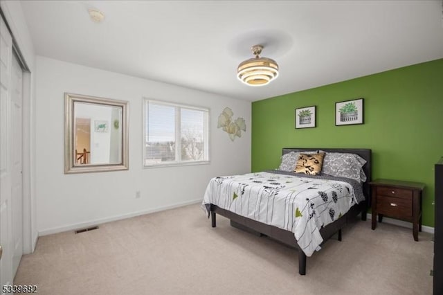 bedroom featuring light carpet, a closet, visible vents, and baseboards