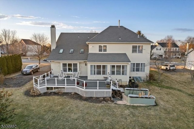 back of house featuring a lawn, a chimney, and a wooden deck