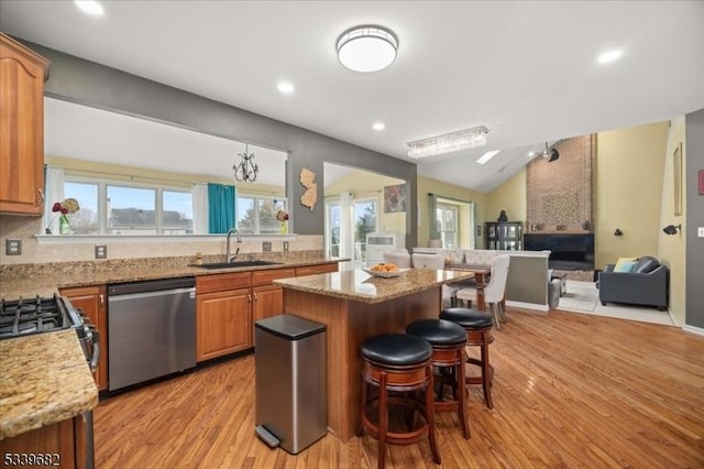 kitchen featuring a breakfast bar area, open floor plan, vaulted ceiling, stainless steel dishwasher, and a sink