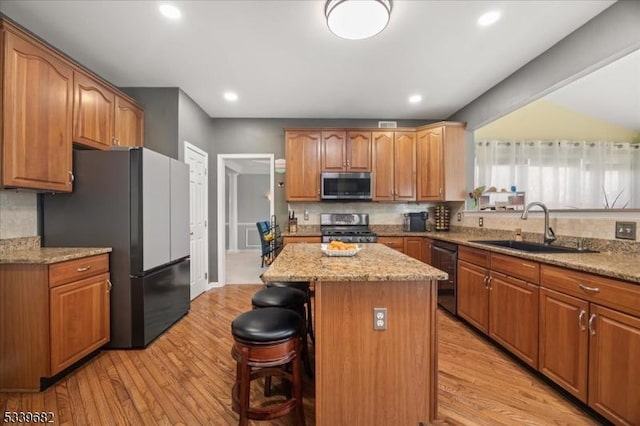 kitchen with a breakfast bar area, a kitchen island, a sink, appliances with stainless steel finishes, and tasteful backsplash