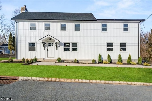 view of front facade with a chimney and a front yard