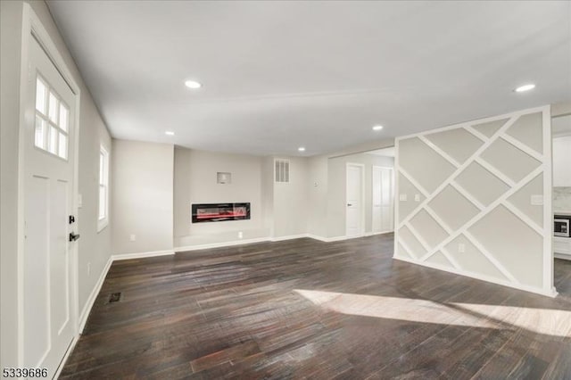 unfurnished living room featuring recessed lighting, dark wood-style flooring, and a glass covered fireplace