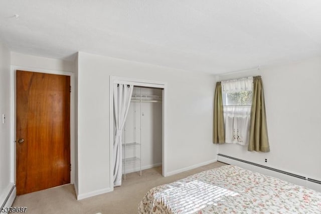 bedroom with light carpet, baseboard heating, a closet, and baseboards