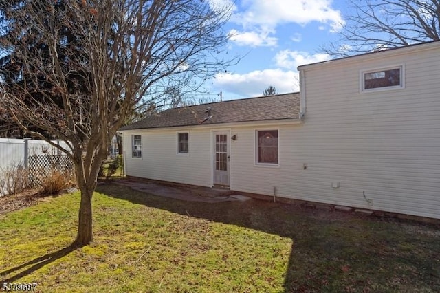 back of property with fence and a lawn