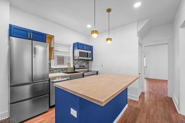 kitchen with blue cabinetry, stainless steel appliances, backsplash, a sink, and a kitchen island