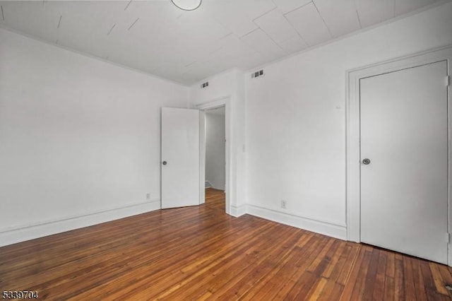 spare room with visible vents, baseboards, and wood finished floors