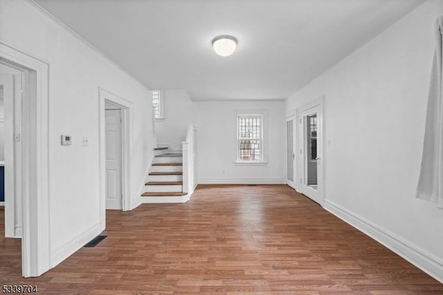 unfurnished room featuring baseboards, stairway, and wood finished floors