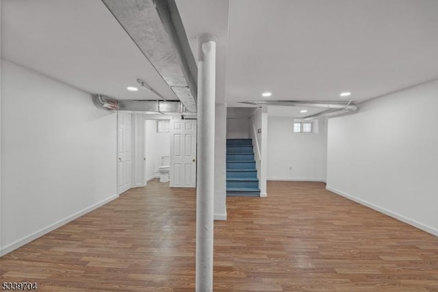 basement featuring stairs, baseboards, and wood finished floors