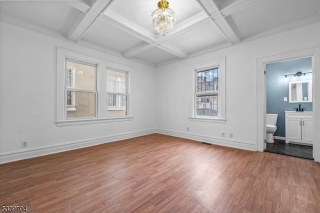 unfurnished bedroom with a notable chandelier, coffered ceiling, a sink, wood finished floors, and baseboards