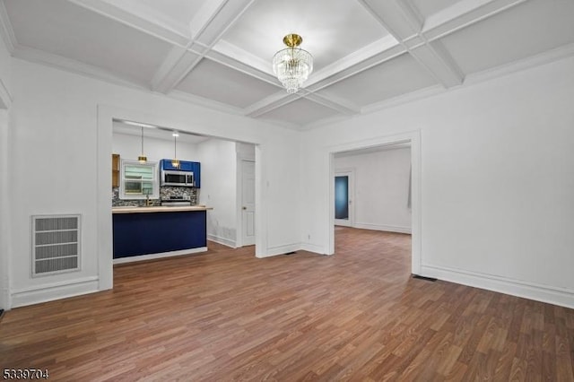 unfurnished living room featuring baseboards, visible vents, coffered ceiling, dark wood-style flooring, and a notable chandelier