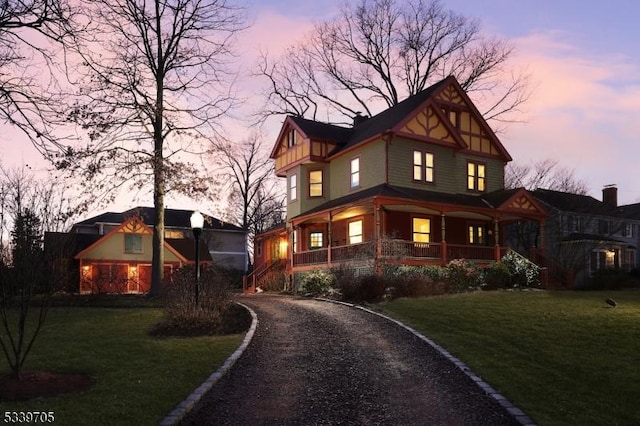 view of front facade featuring covered porch, driveway, and a lawn