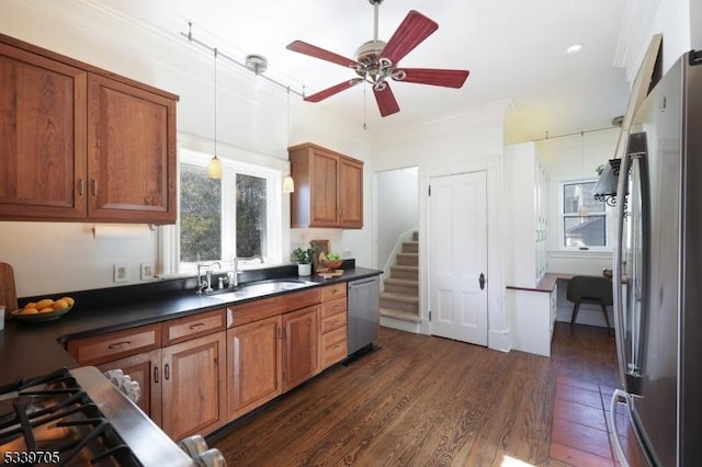 kitchen featuring dark countertops, brown cabinets, dark wood-type flooring, stainless steel appliances, and a sink