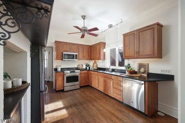 kitchen featuring stainless steel appliances, dark wood-type flooring, a sink, brown cabinets, and dark countertops