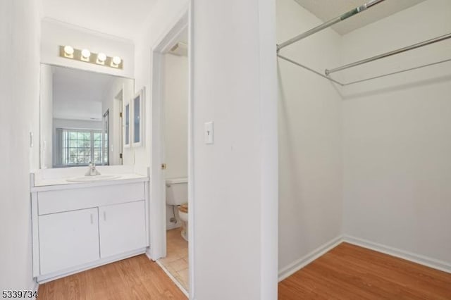 full bath with baseboards, vanity, toilet, and wood finished floors