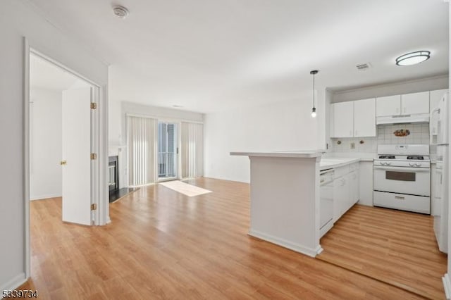 kitchen with white appliances, open floor plan, a peninsula, light countertops, and white cabinetry