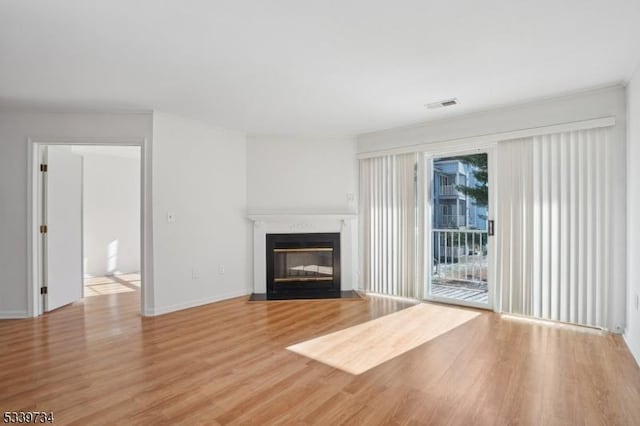 unfurnished living room with a fireplace with flush hearth, baseboards, visible vents, and light wood finished floors