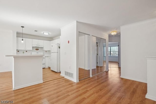 kitchen featuring white appliances, visible vents, white cabinets, light countertops, and pendant lighting