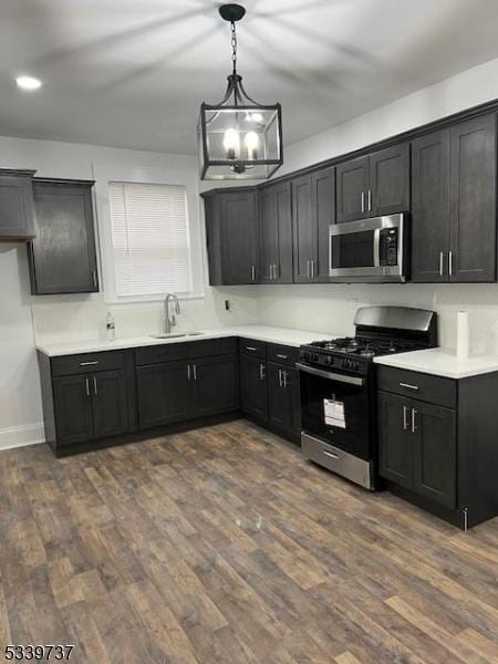 kitchen featuring stainless steel appliances, light countertops, decorative light fixtures, and dark cabinets