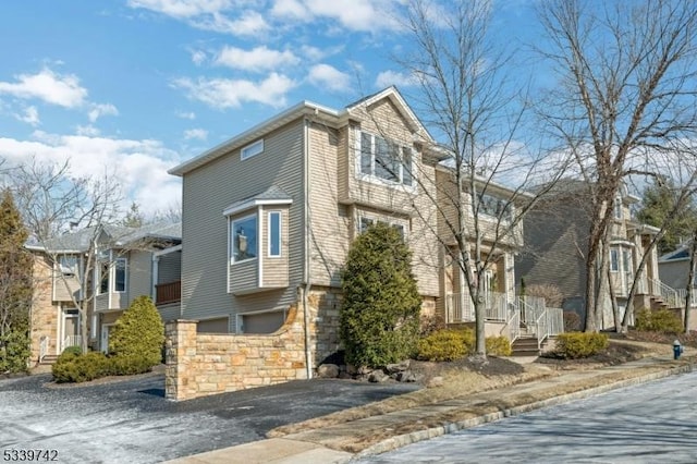 view of front facade featuring a garage, stone siding, and driveway