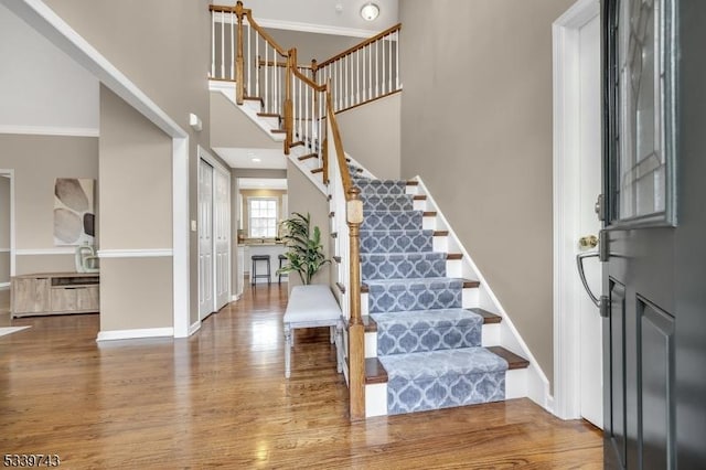 foyer featuring stairs, wood finished floors, a towering ceiling, and baseboards