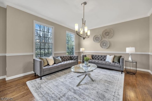 living room with a chandelier, crown molding, baseboards, and wood finished floors